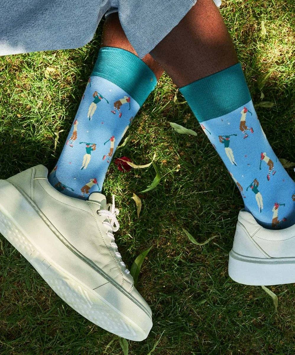 Hole-In-One Socken auf grünem Golfplatz neben Golfball und Schuh